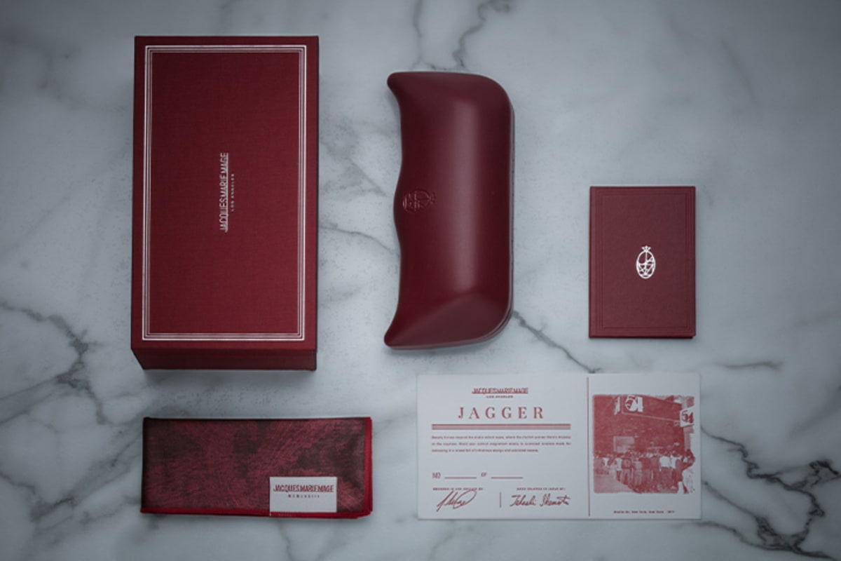 Jacques Marie Mage signature burgundy packaging and accessories, featuring Italian-handcrafted leather case, microfiber cleaning cloth/pocket square, hard-shelled, silk fabric-covered packaging, and letterhead press certificate with limited edition serial number and craftsmen signature. - Side Profile