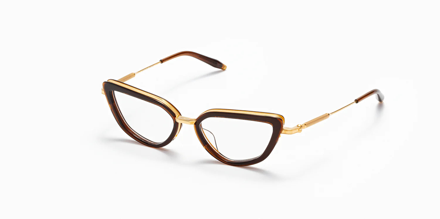 "Venus" frame model by Akoni in the crystal brown and gold colorway, featuring a shiny dark brown geometric cat eye frame front with a polished gold trim that extends to the temples, which are capped with Akoni's signature acetate temple tips.