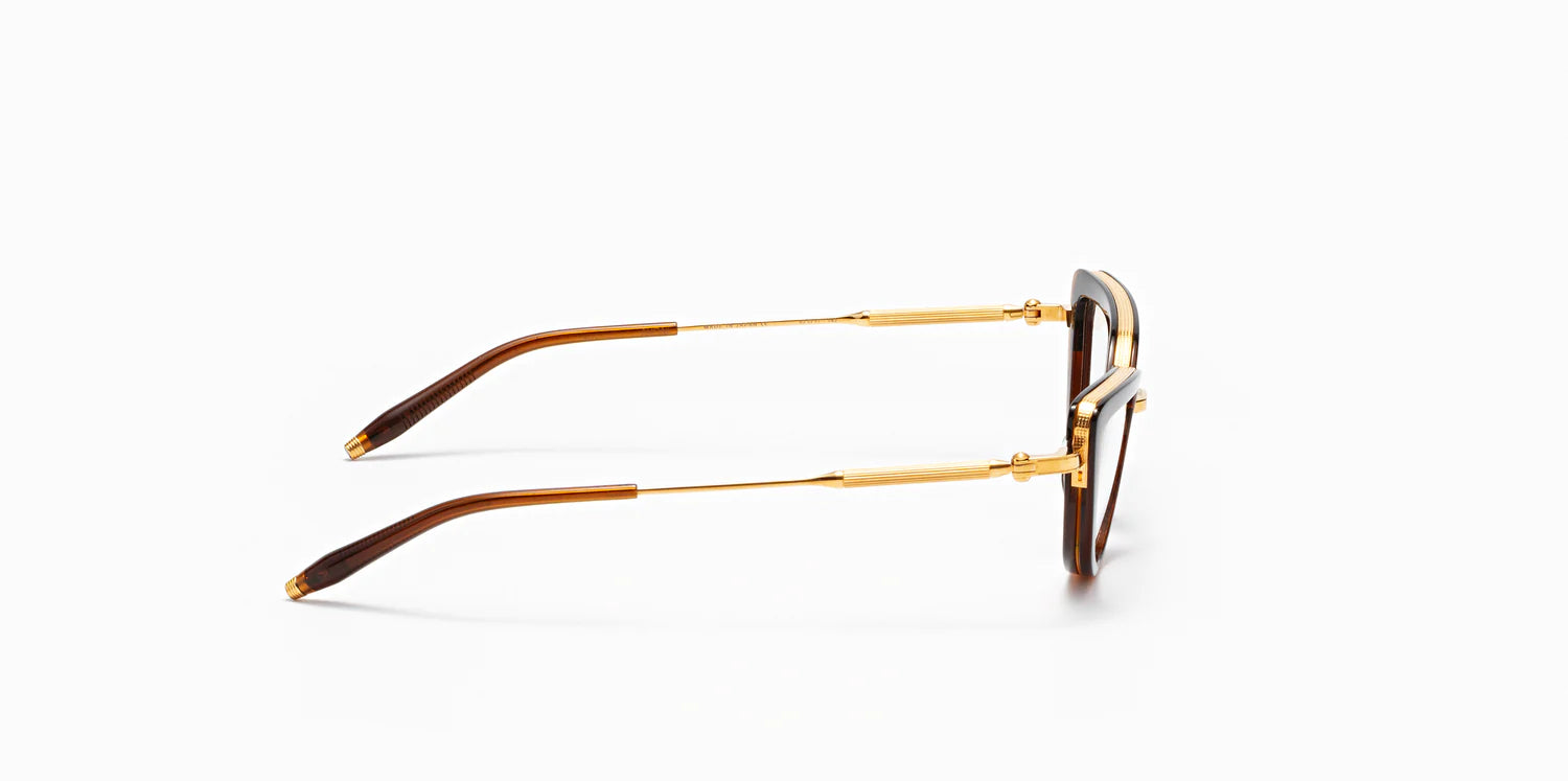 Side of "Venus" frame model by Akoni in the crystal brown and gold colorway, featuring a shiny dark brown geometric cat eye frame front with a polished gold trim that extends to the temples, which are capped with Akoni's signature acetate temple tips.